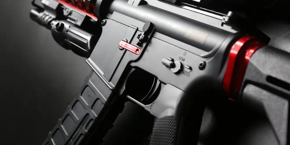 Picture of an AR 15 Gun shadowed with red accents, focus on the trigger